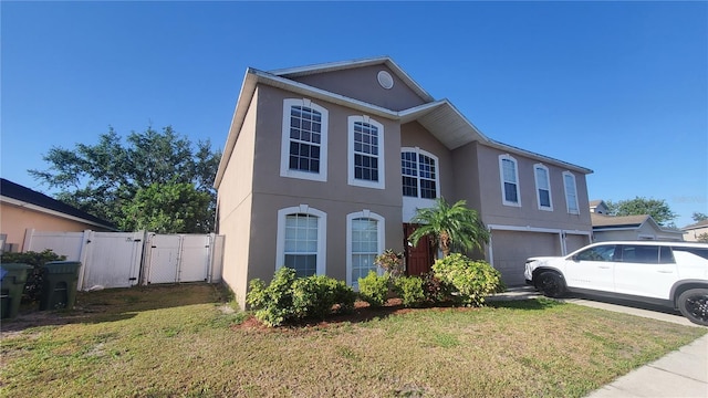 view of front of home featuring an attached garage, a front lawn, a gate, and stucco siding