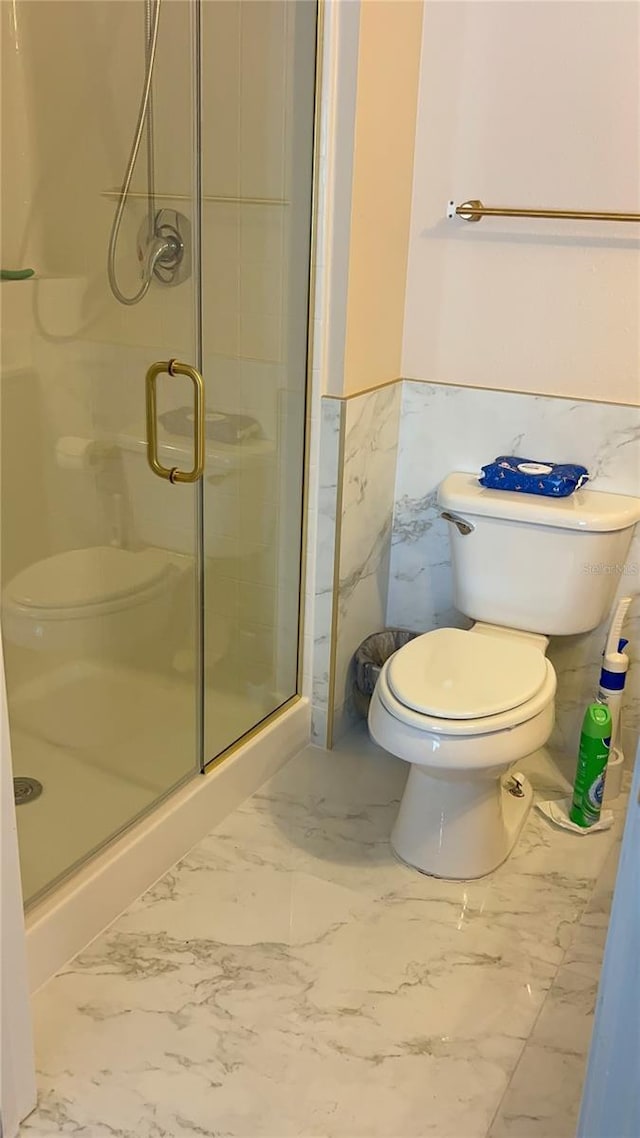 full bathroom with a wainscoted wall, marble finish floor, a shower stall, and toilet