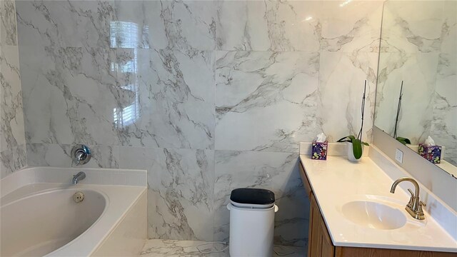 bathroom with tile walls, vanity, a bathtub, and marble finish floor