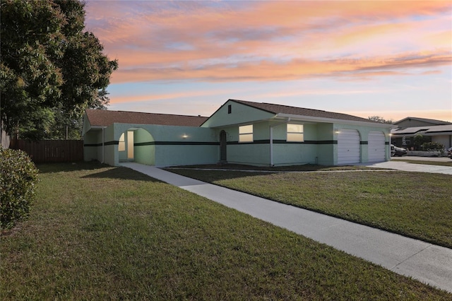 ranch-style home with fence, concrete driveway, a front lawn, and stucco siding