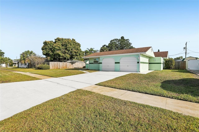 view of front of property with concrete driveway, a front lawn, and fence