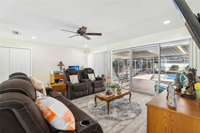 living area with recessed lighting, visible vents, light wood-type flooring, a textured ceiling, and ceiling fan