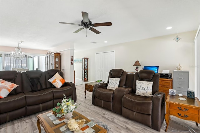 living room with ceiling fan with notable chandelier, visible vents, and light wood finished floors