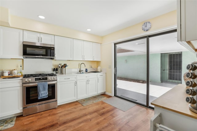 kitchen with white cabinetry, light wood-style flooring, stainless steel appliances, and a sink