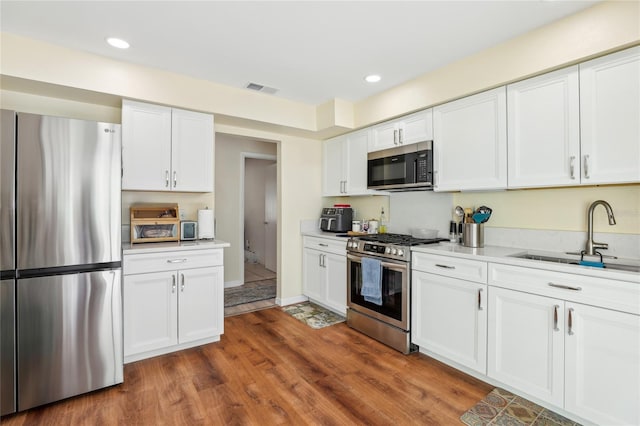 kitchen featuring white cabinets, visible vents, a sink, and appliances with stainless steel finishes