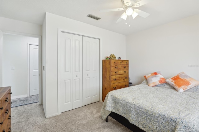 bedroom featuring light colored carpet, ceiling fan, visible vents, and a closet
