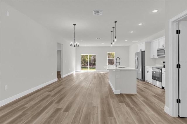 15823 SW 27th Avenue Rd, Ocala, FL 34473 - kitchen with white cabinetry, a sink, open floor plan, stainless steel appliances, and light wood-style flooring