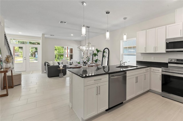 kitchen with white cabinets, a sink, a peninsula, appliances with stainless steel finishes, and open floor plan