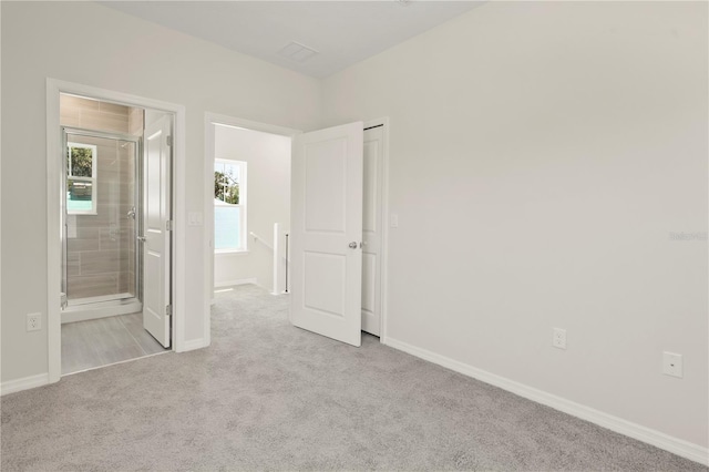 unfurnished bedroom with carpet flooring, baseboards, and ensuite bathroom