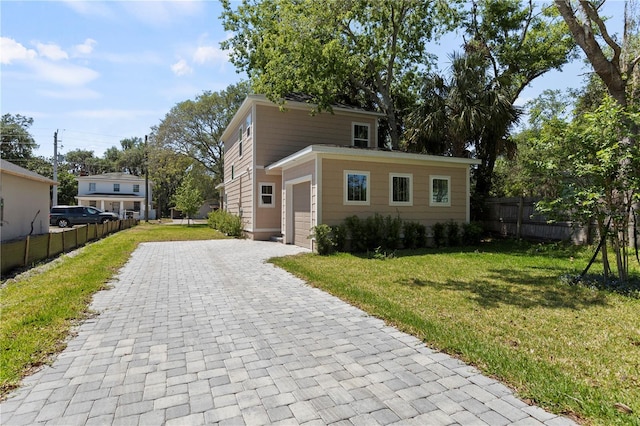 view of front of house featuring a front lawn, fence, decorative driveway, and a garage