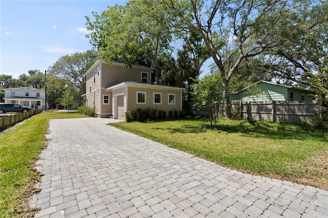 view of front of property with fence, an attached garage, a front yard, and decorative driveway