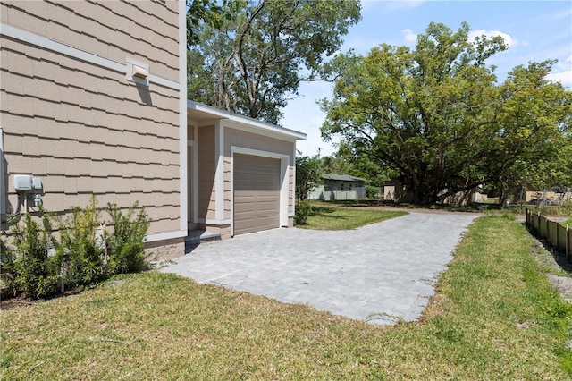 view of yard with an attached garage and decorative driveway