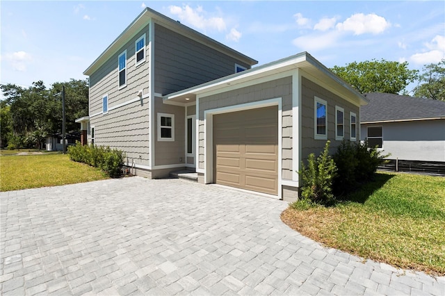 view of side of home featuring an attached garage, a yard, and decorative driveway