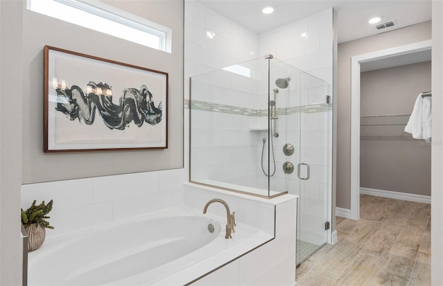 2729 Serenity Meadow Dr, Kissimmee, FL 34744 - bathroom featuring wood finished floors, visible vents, a walk in closet, a bath, and a stall shower