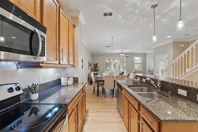 kitchen with visible vents, brown cabinets, a sink, ornamental molding, and stainless steel appliances