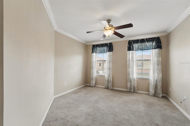 carpeted spare room with baseboards, ornamental molding, and a ceiling fan