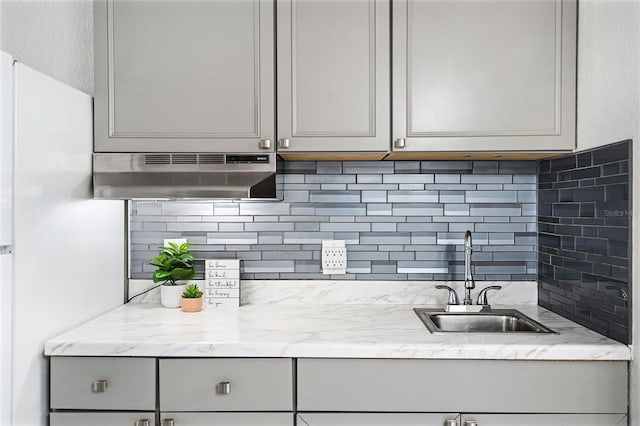 43420 Hwy 27 Unit 121, Davenport, FL 33837 - kitchen with under cabinet range hood, light stone counters, a sink, backsplash, and gray cabinetry