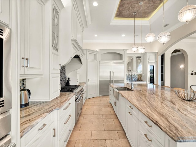 971 Golden Bear Dr, Reunion, FL 34747 - kitchen with white cabinets, a tray ceiling, a sink, arched walkways, and decorative backsplash