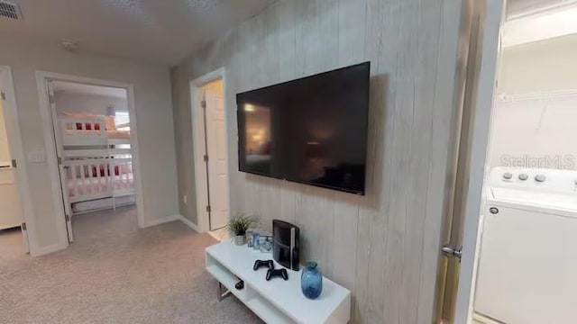 living area with visible vents, baseboards, light colored carpet, and washer / clothes dryer
