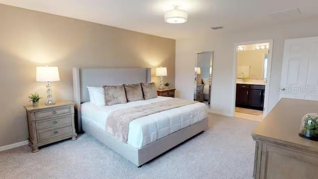 bedroom with ensuite bath, light carpet, and baseboards