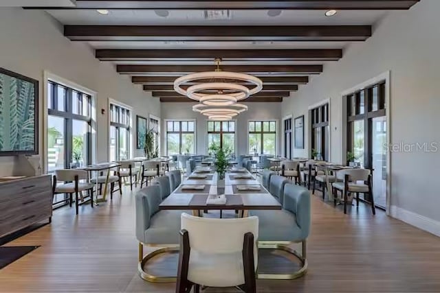 dining room featuring baseboards, wood finished floors, beamed ceiling, and an inviting chandelier