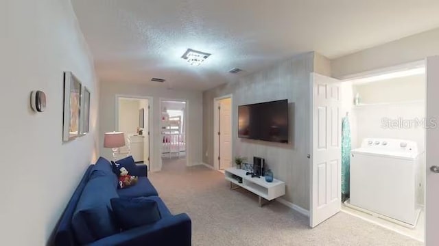 living area with light colored carpet, washer / dryer, visible vents, and baseboards