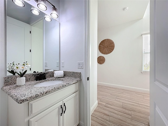 bathroom with baseboards, wood finished floors, and vanity