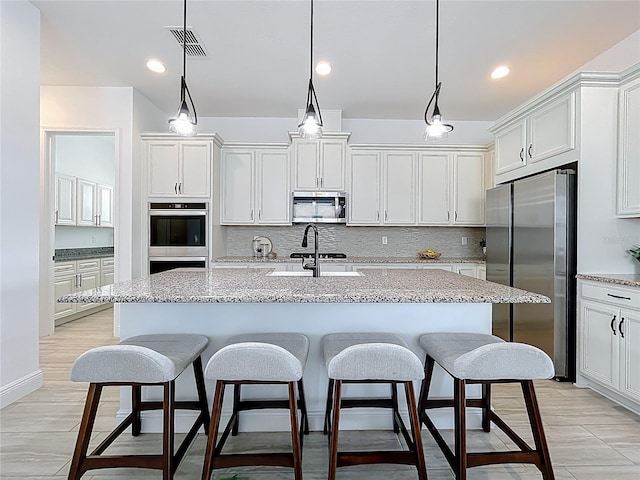 kitchen with a breakfast bar area, visible vents, appliances with stainless steel finishes, and tasteful backsplash