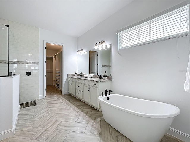 full bath with a freestanding bath, a walk in shower, vanity, baseboards, and a spacious closet