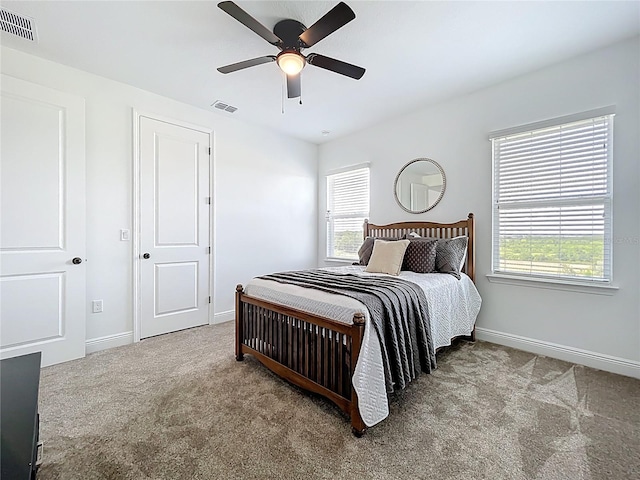 bedroom featuring carpet flooring, visible vents, and multiple windows