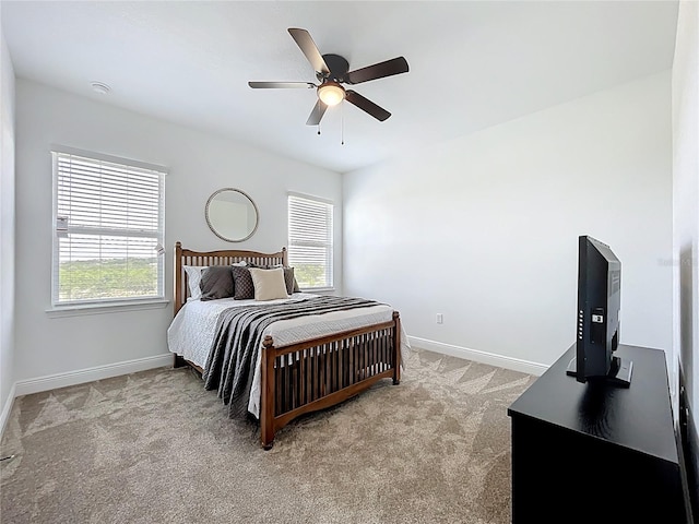 bedroom with multiple windows, ceiling fan, light carpet, and baseboards