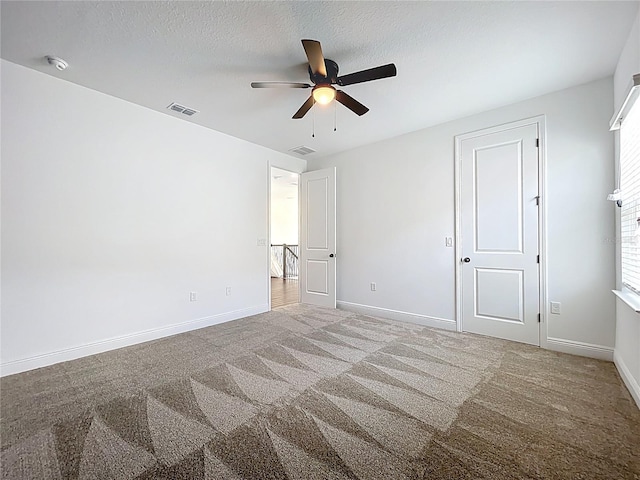 unfurnished bedroom featuring a textured ceiling, visible vents, carpet floors, and baseboards