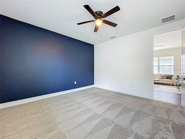 unfurnished room with visible vents, a ceiling fan, baseboards, and carpet floors