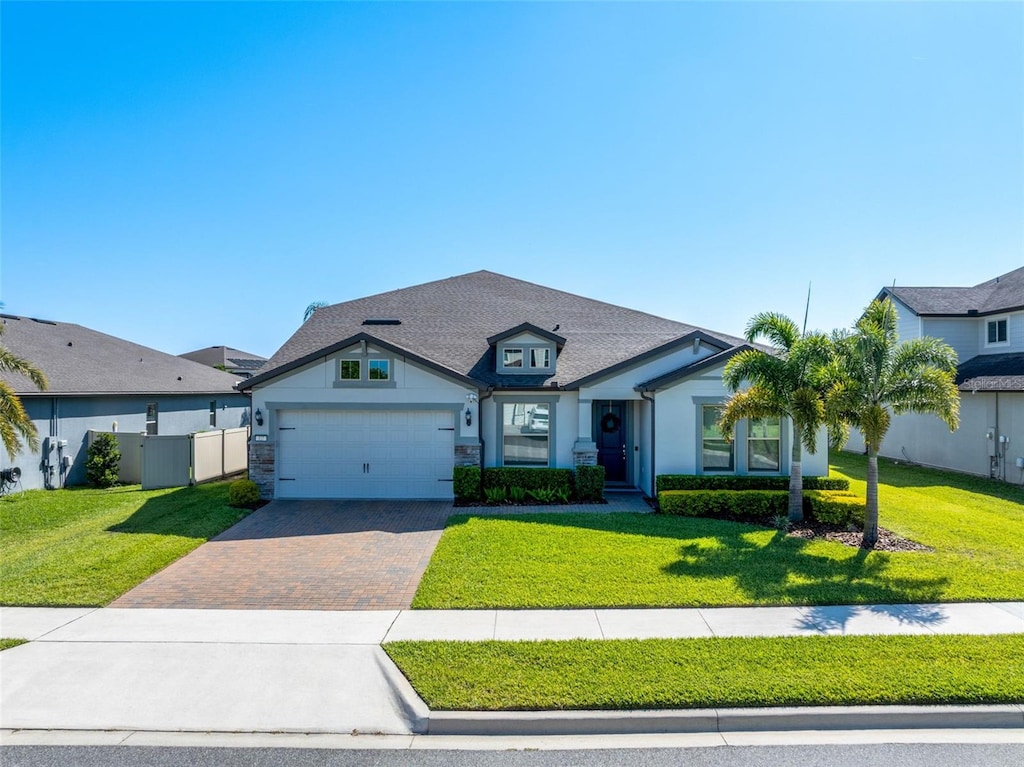 view of front of home featuring a garage, fence, decorative driveway, and a front yard