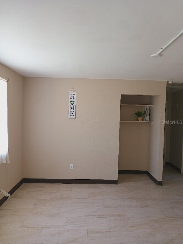 unfurnished room with baseboards