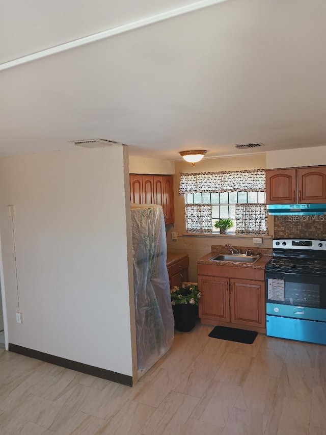 kitchen featuring brown cabinets, under cabinet range hood, visible vents, a sink, and electric range oven