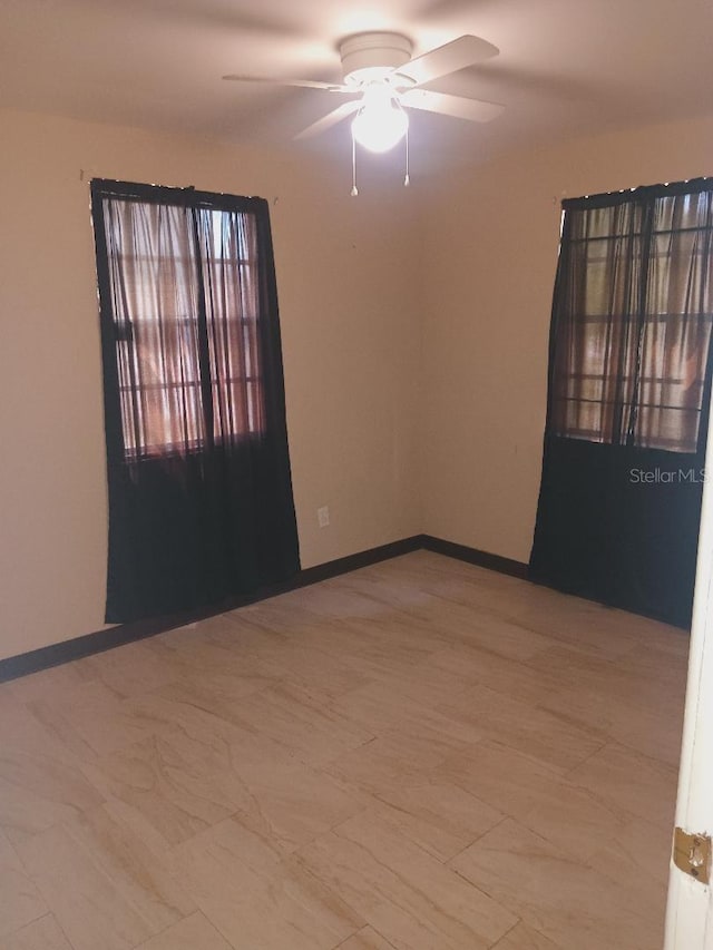 empty room with a ceiling fan and baseboards