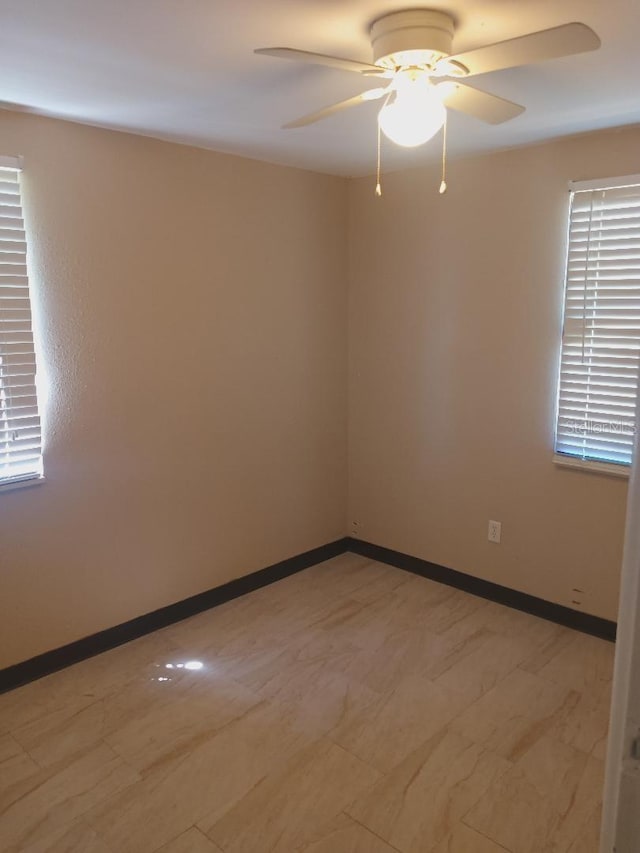 unfurnished room with ceiling fan and baseboards