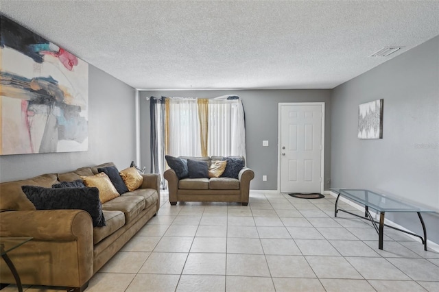 living area featuring light tile patterned floors, a textured ceiling, and visible vents