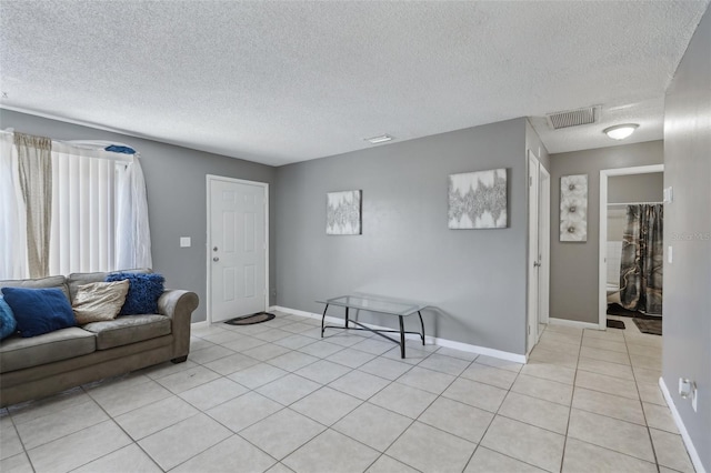 living area featuring visible vents, light tile patterned floors, and a textured ceiling