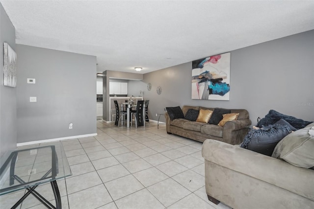 living room featuring baseboards, a textured ceiling, and light tile patterned flooring