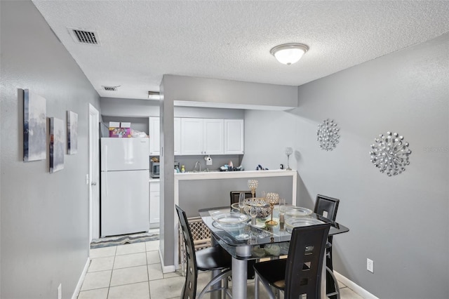 dining area featuring baseboards, visible vents, and a textured ceiling