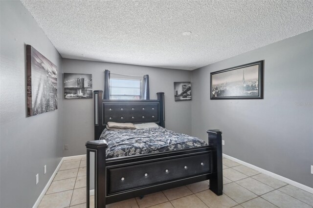 tiled bedroom featuring baseboards and a textured ceiling