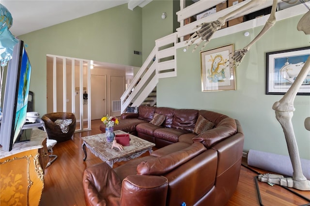 living room with visible vents, high vaulted ceiling, wood finished floors, and stairway