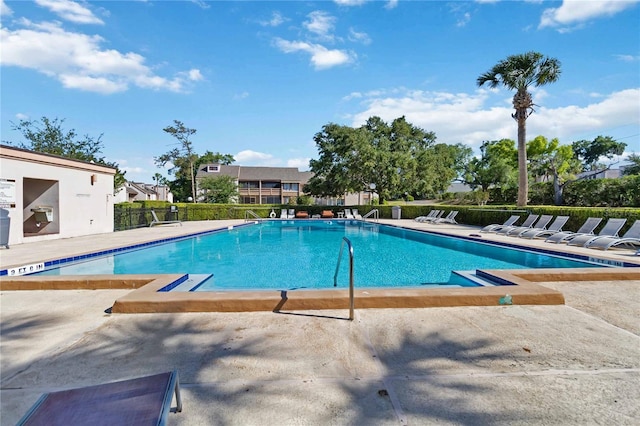 community pool with a patio and fence
