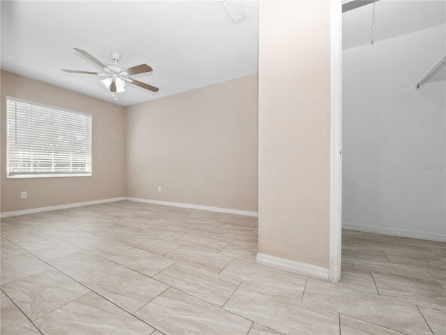 spare room with a ceiling fan and baseboards