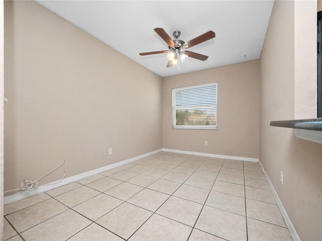 empty room featuring ceiling fan, baseboards, and light tile patterned floors