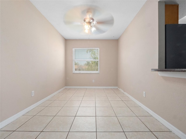 spare room featuring ceiling fan, baseboards, and light tile patterned flooring