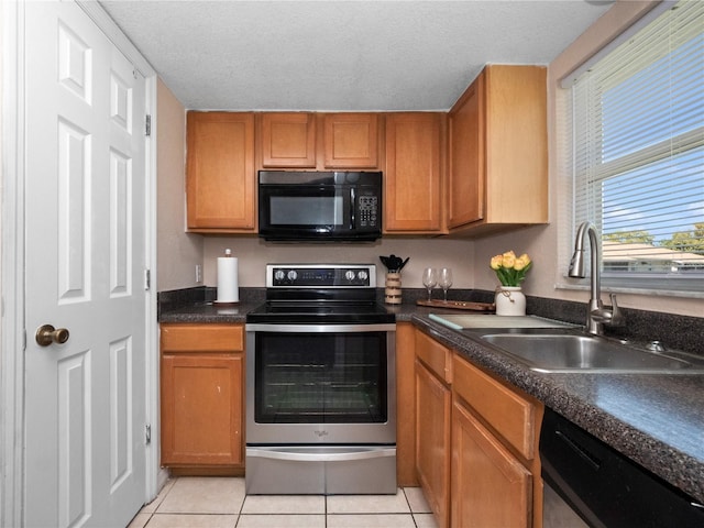 kitchen featuring light tile patterned floors, a sink, brown cabinets, and appliances with stainless steel finishes