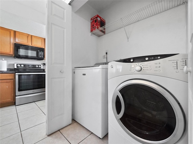 laundry area with washing machine and dryer, laundry area, and light tile patterned floors